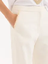 Pantalón de vestir blanco, de corte recto y amplio, confeccionado en jacquard. Se ajusta a la cintura con cierre, gancho pantalonero y botón interno.