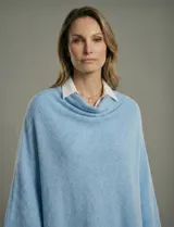 Poncho tejido de punto liso, color celeste claro, con cuello tipo chimenea o vuelto.