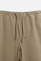 Pantalón de hombre color beige, corte carrot fit, con cintura elástica ajustable con cordón, bolsillos frontales y bolsillo trasero de plastrón.