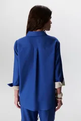 Camisa verde militar de manga larga con puños color crema, cuello clásico y cierre frontal con botones. Tiene un bolsillo en el pecho con bordado de una palmera color crema.