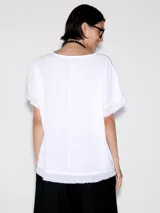 Blusa de algodón blanca con diseño de capas y flecos en el hem.