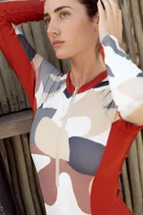 Enteriza de surf de mangas largas con cierre en el busto. Diseño con paneles laterales en color ladrillo y estampado abstracto en tonos tierra.