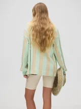 Cardigan a rayas horizontales en tonos beige y negro, de corte holgado y abierto, con botones metálicos y logo MUTMA bordado en el frente.
