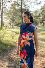 Vestido midi azul marino con estampado de flores rojas, naranjas y rosas. Tiene cuello drapeado y corte ajustado al cuerpo.