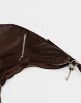 Cartera tipo saca color marrón oscuro de cuerina, con asa corta para el hombro, cierre superior y bolsillos frontales con cierre.