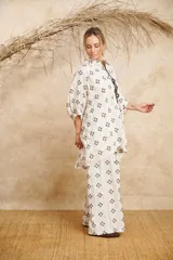 Pantalón palazzo color crudo con bordado de flores negras y cinto de la misma tela.