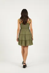 Vestido corto color rosado claro, con breteles finos anudados con borlas, escote redondo y diseño escalonado con frunces.