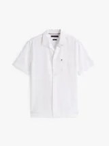 Camisa de manga corta blanca con textura seersucker, cuello clásico y cierre frontal de botones. Presenta un pequeño logo bordado en el pecho.