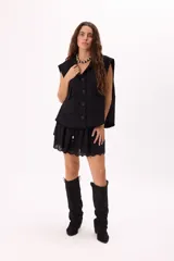 Minifalda color crema con bordado calado tipo broderie, cintura elastizada con cordón ajustable y detalle de cuentas de madera. Diseño de doble capa con volados.