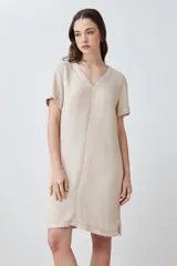 Vestido corto color beige melange, de lino, con cuello en V y mangas cortas. Presenta pespuntes verticales en contraste.