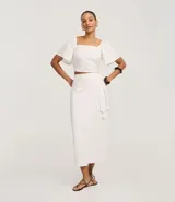 Pollera midi recta color blanco, de laise con bordados geométricos y lazo en la cintura.