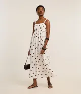 Vestido midi evasé sin mangas, confeccionado en tejido airflow color blanco con estampado de lunares marrones. Presenta escote corazón, breteles anchos con elásticos y lastex en la espalda.