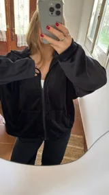 Campera negra oversize de tela tipo plush con cierre frontal y capucha.