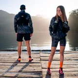 Campera cortaviento gris con estampado camuflado, cierre frontal completo, capucha ajustable y logo de la marca en el pecho.