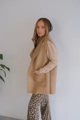 Chaleco largo color beige, con solapas y bolsillos delanteros con borde de corderito.