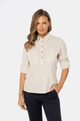 Camisa color beige de lino, de manga larga con botones metálicos personalizados y presilla en la manga. Tiene cuello clásico, cierre frontal parcial con botones y bolsillo de parche en el pecho.