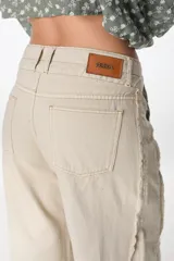 Pantalón jean color beige, de corte recto y tiro alto, con bolsillos delanteros y traseros, y detalle desflecado en los laterales.