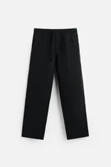Pantalón negro de corte amplio, con cintura elástica ajustable con cordón, bolsillos laterales y traseros.