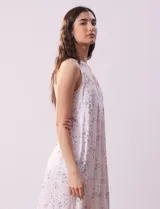 Camisón corto de tejido suave con estampado de rosas rosadas sobre fondo lila. Tiene escote redondo con detalle de puntilla blanca y botones.