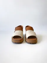 Sandalia de cuero color camel y crudo, con tira ancha sobre los dedos, tira al tobillo con hebilla y suela track.