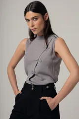 Musculosa negra con cuello alto y detalle de botones decorativos en el lateral.