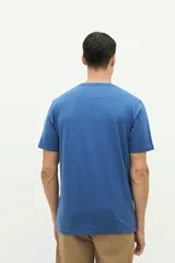 Remera color rosa pálido de manga corta con cuello redondo y estampado frontal con texto y diseño floral en tonos azules.