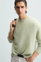 Sweater verde claro tejido con lana y alpaca, de corte regular, cuello redondo y manga larga con terminaciones en rib.