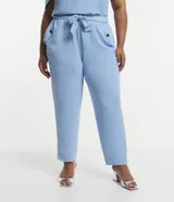 Pantalón de crepé celeste, modelo zanahoria, con elástico y lazo en la cintura. Presenta bolsillos traseros simples y bolsillos delanteros con solapas y botones metalizados.