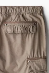 Pantalón cargo color marrón topo, de corte relajado, confeccionado en popelina de algodón. Cuenta con bolsillos al bies, bolsillos traseros con solapa y bolsillos laterales en las piernas con solapa y botones a presión.
