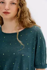 Remera blanca de lino con tachas plateadas en el frente, cuello redondo y mangas cortas.