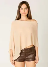 Poncho color beige de tejido liviano con destellos sutiles.