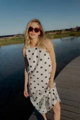 Vestido midi blanco con estampado de lunares negros, sin mangas y corte holgado.