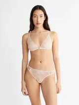 Conjunto de lencería color rosa pálido, compuesto por un corpiño triangular de encaje floral sin aro ni relleno, con tirantes finos regulables y cierre frontal metálico, y una bombacha tipo tanga de encaje floral con laterales de tul.