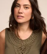 Blusa sin mangas color verde oliva, con cuello redondo y detalle texturizado de macramé en el escote.