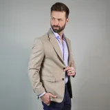 Saco de lana color beige, de corte clásico, con solapas de muesca, cierre de dos botones, bolsillo en el pecho y bolsillos laterales con solapa.