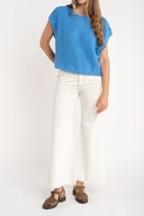 Chaleco de punto color beige con lurex, de corte recto y mangas cortas. Tejido calado con pequeños agujeros.