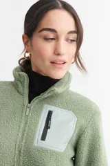 Campera negra de corderito con cierre frontal y cuello alto. Tiene un bolsillo con cierre en el pecho y bolsillos laterales.