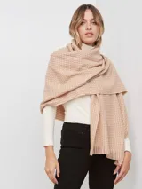 Bufandón tejido de poliéster, color rosa pálido con textura jaspeada en tonos pastel (naranja, lila, gris). Presenta un tejido grueso y flecos en los bordes.