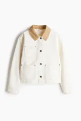 Campera de denim color crudo con cuello de pana color beige, con botones al frente, corte holgado, bolsillos superiores y bolsillos parche delanteros, hombros caídos y puños abotonados.