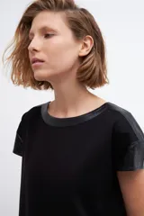 Vestido negro de corte recto y manga corta, con cuello y hombros con apliques de cuero ecológico negro.
