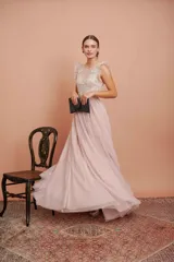 Vestido largo de fiesta color rosado con lunares blancos. Tiene cuerpo de micro tul bordado con volados en los hombros y falda de tul con forro. Incluye cinturón de raso al tono.