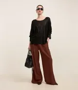 Blusa negra de punto liviano con escote redondo, manga larga y sisa raglán. Tiene una malla con lámina metálica.