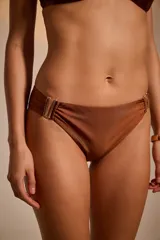 Bombacha de bikini vedetina color cobre, con detalle de frunce y apliques metálicos dorados en los laterales.