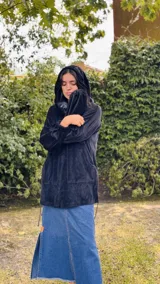 Buzo tipo canguro oversize de tela plush, color azul claro. Presenta capucha, cierre frontal parcial con cordón turquesa y bolsillos canguro frontales. Las mangas son largas y abullonadas con puños ajustados.