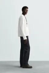 Camiseta blanca de manga larga con cuello redondo y textura cuadriculada.