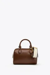 Bolso marrón formato city con asa doble de mano con detalles metálicos y correa interior extraíble en tejido canvas con posición bandolera. Bolsillo interior con cierre mediante cremallera metálica.