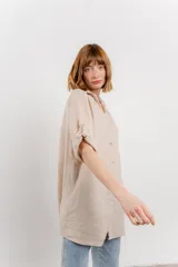 Camisa amarilla de lino con corte recto y calce suelto. Tiene cuello camisero, botones en el frente y mangas cortas con presilla y botón.