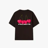 Camiseta oversize negra con estampado trasero de cuatro cerezas rosadas en forma de corazón con las letras "Nude" sobre ellas, y el texto "PROJECT®" debajo.