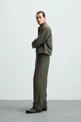 Pantalón verde oscuro de corte recto, con cintura elástica, bolsillos laterales y un bolsillo trasero. Cierre frontal con cremallera y botón.