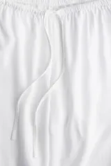 Pantalón blanco de tejido liviano con lino, de tiro bajo con elástico revestido y cordón para ajustar en la cintura, bolsillos al bies y piernas rectas.